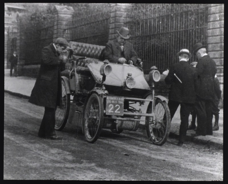 George Lanchester lighting his pipe, next to the 8hp gold medal Phaeton at the Reading control point on the 1,000 mile trial